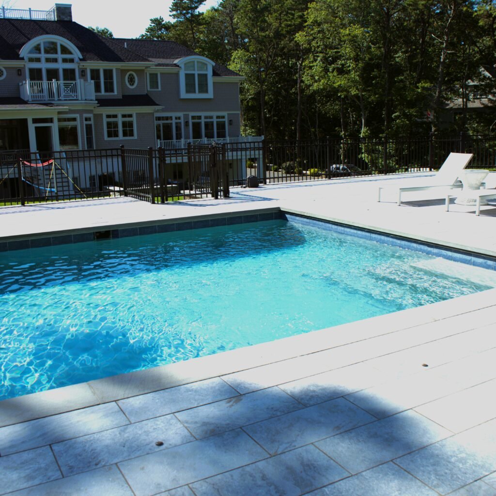 Outdoor residential swimming pool with clean water and stone deck at a Cape Cod property