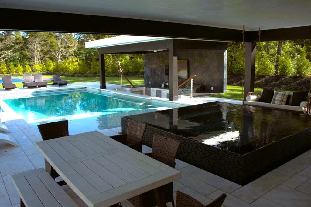 Outdoor swimming pool with covered patio, seating area, and modern layout at a residential property on Cape Cod