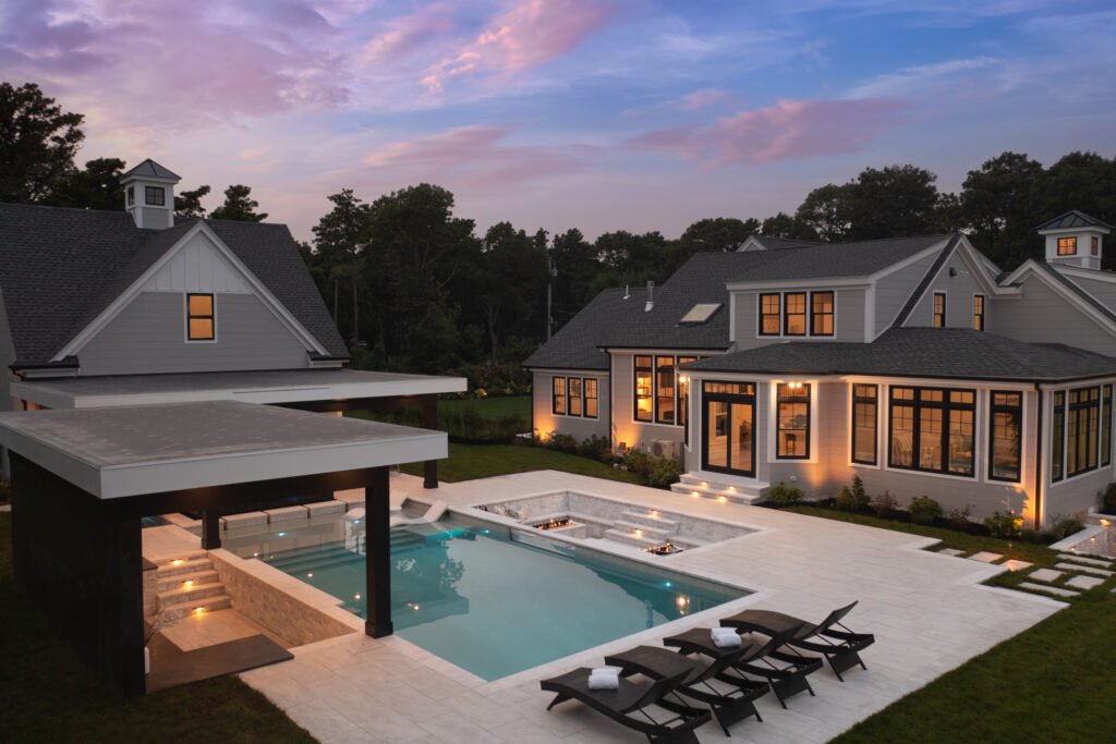 Outdoor swimming pool with modern design and seating area at a residential property on Cape Cod during evening light