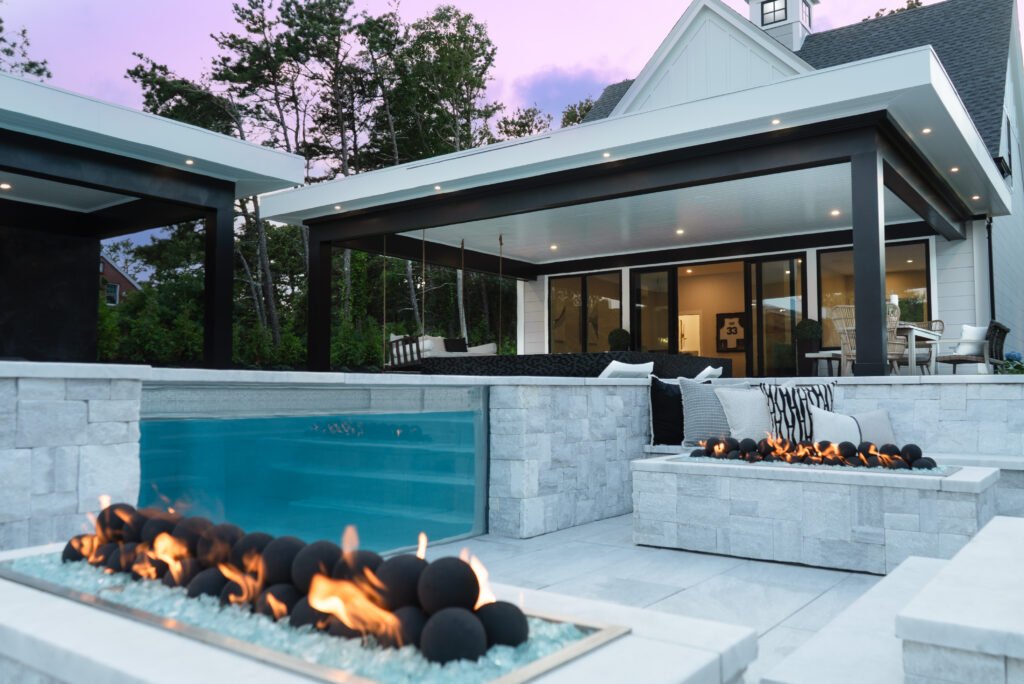 Modern outdoor swimming pool with fire pit design at a Cape Cod residential property